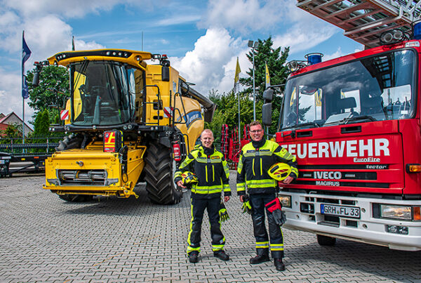 Henning Edler und Marco Weber vor Mähdrescher und Drehleiter.