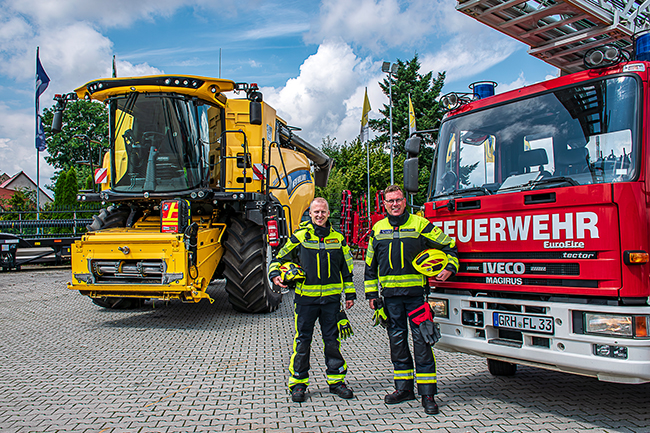 Henning Edler und Marco Weber vor Mähdrescher und Drehleiter.
